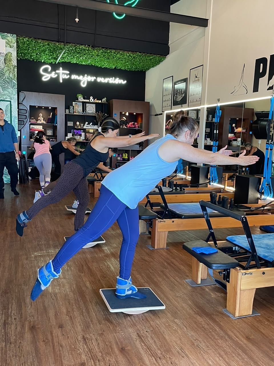 Alumnas de pie sobre tablas de equilibrio, apoyadas en una pierna con los brazos extendidos al frente