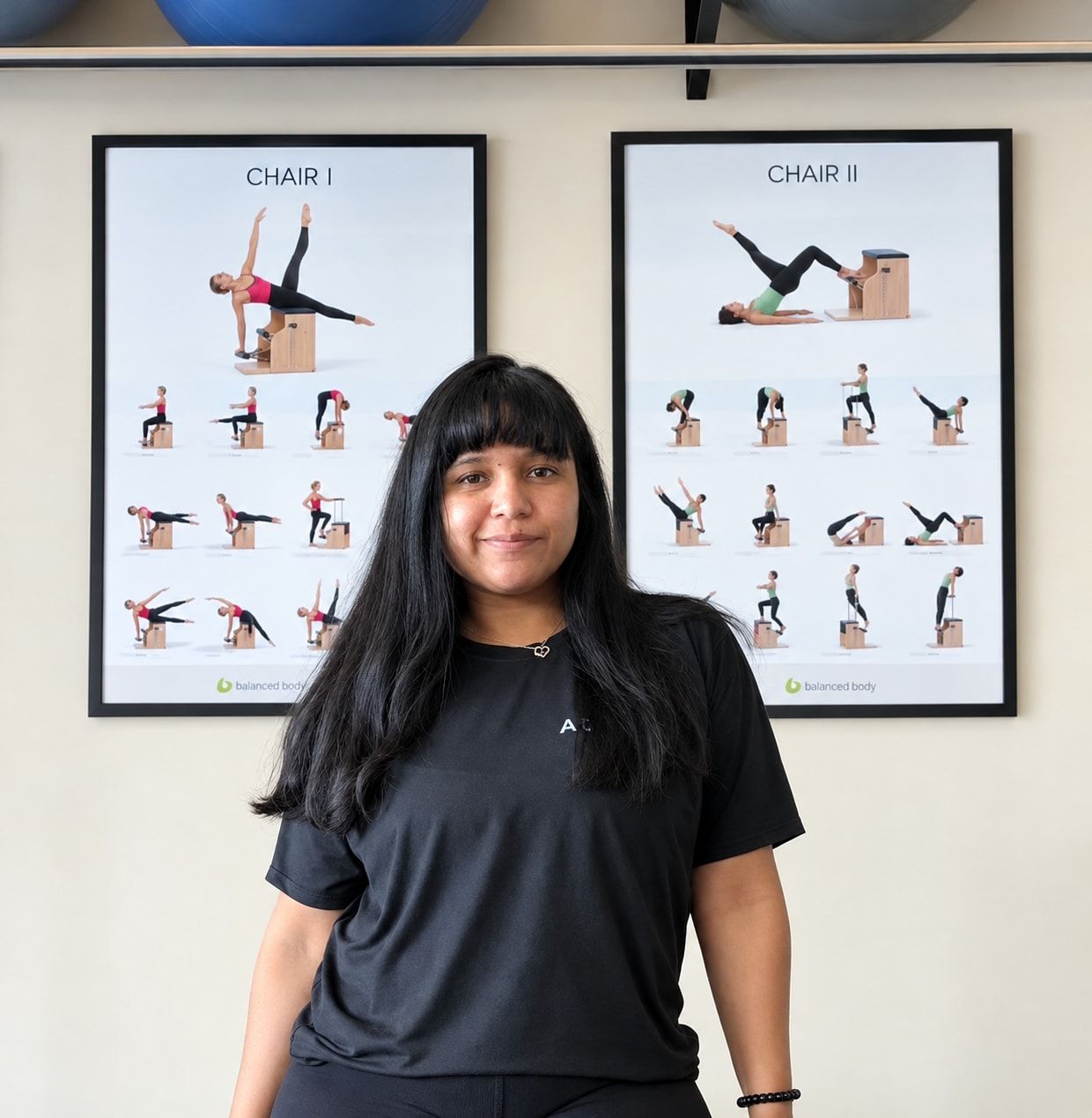 Diana Allen, fisioterapeuta e instructora, de pie frente a los pósteres de ejercicios del estudio